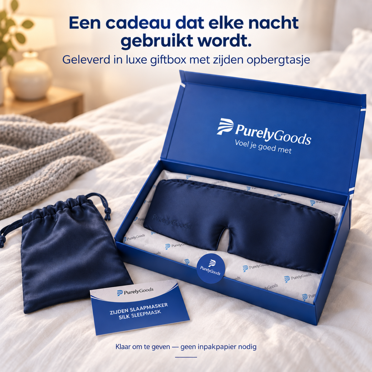 Marineblauw zijden slaapmasker van PurelyGoods in luxe blauwe giftbox met zijden opbergtasje op een bed